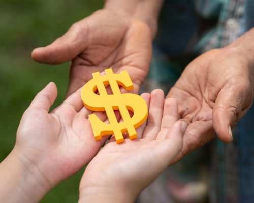 The yellow dollar symbol on hands of elderly and child for the investment or saving of people with differences diversity for insurance, education, safety life for good and stable in future of family